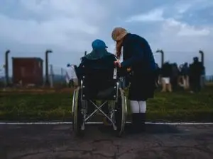 Pflegende Angehörige mit Person im Rollstuhl